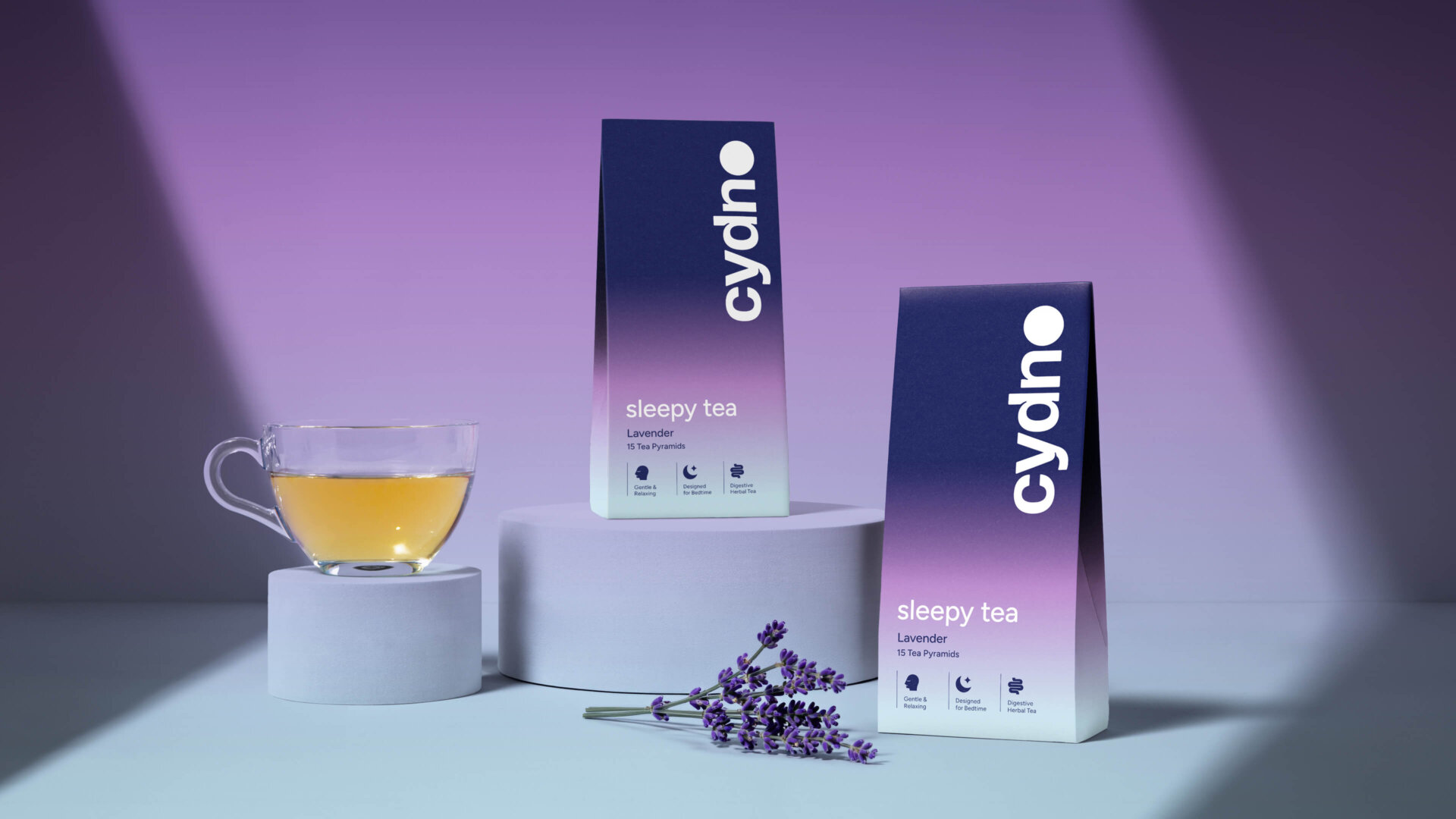 Two Cydno Lavender sleepy tea cartons beside a glass of amber tea and a fresh lavender sprig