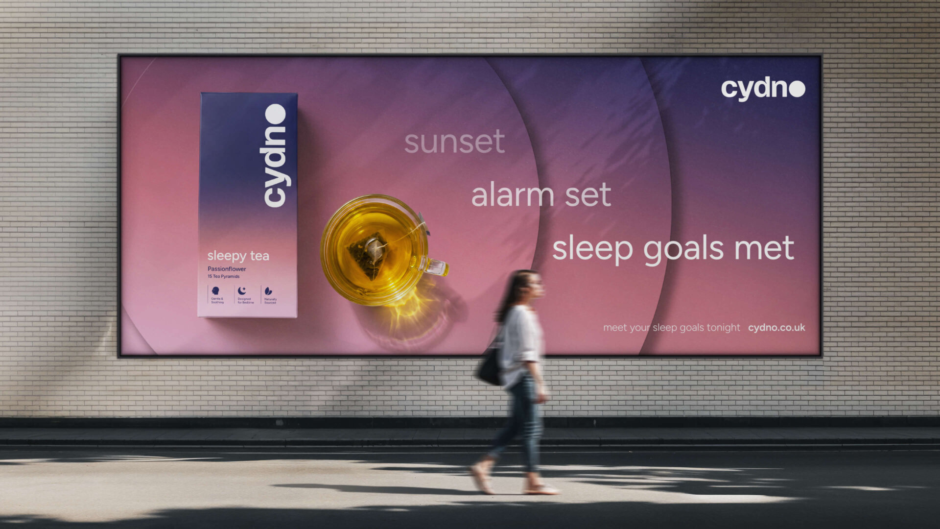 Cydno underpass billboard reading 'sunset, alarm set, sleep goals met' beside a glass of tea